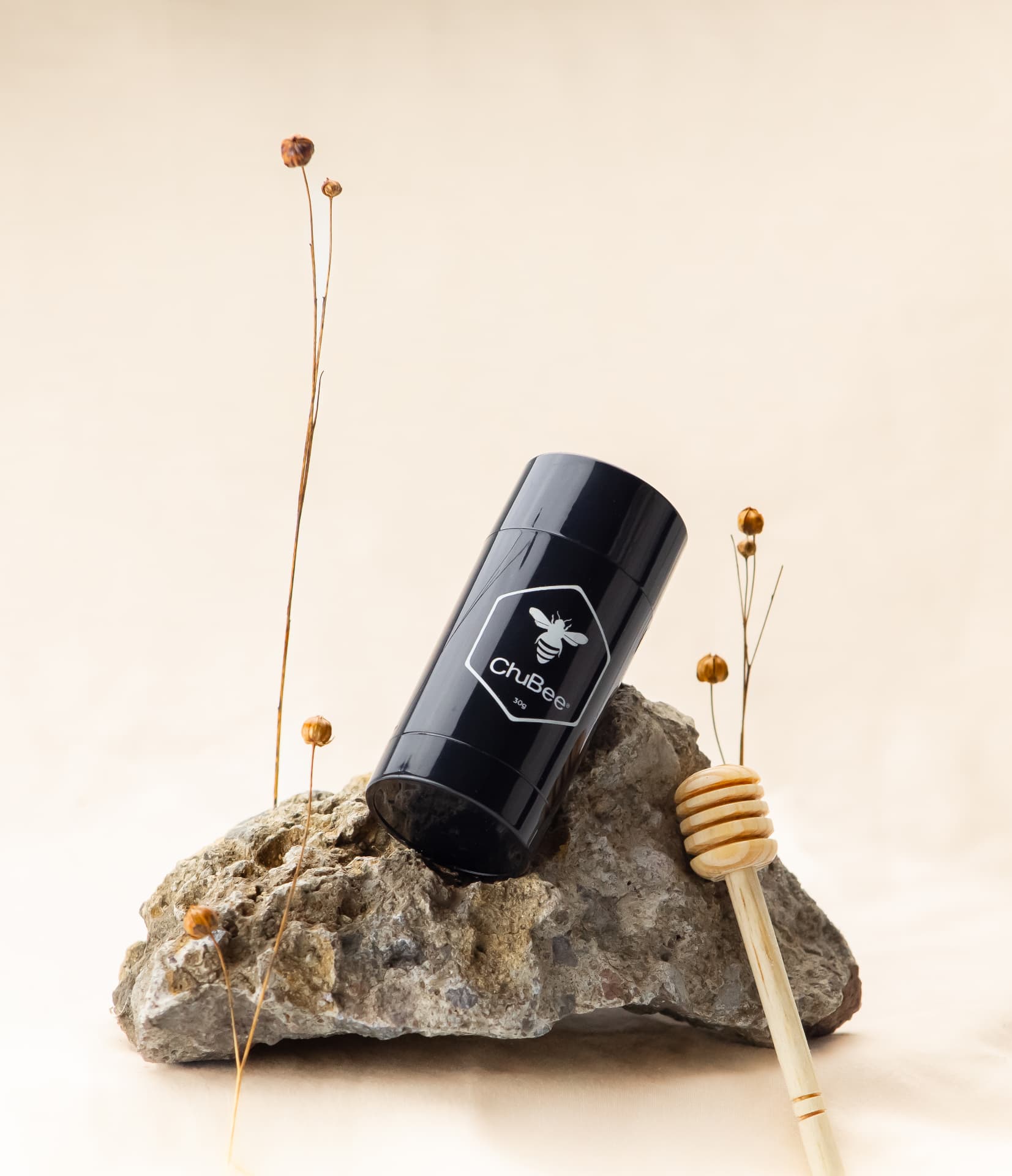 Barra ChuBee sobre una piedra gris con ramas secas y cucharón de miel